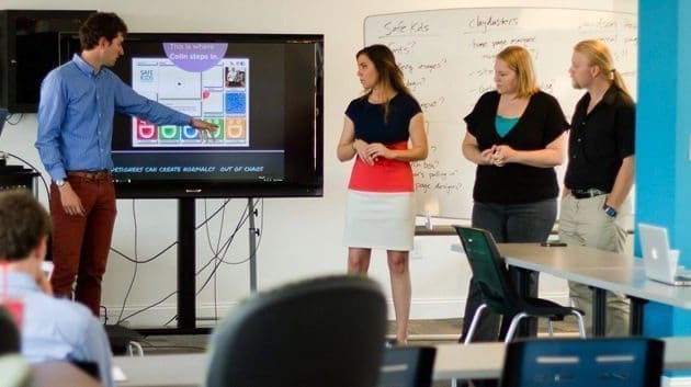 Young professionals giving presentation on large television screen